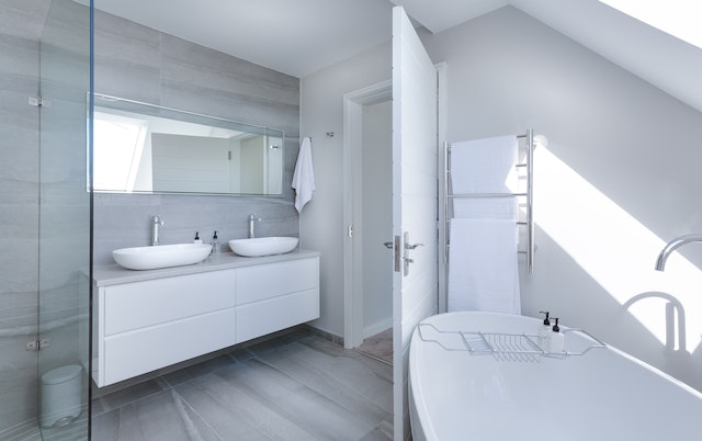 newly renovated white bathroom with large bathtub and double vanity